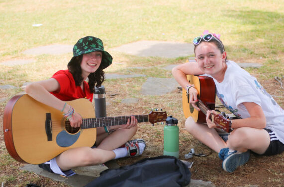 Two campers playing guitar.