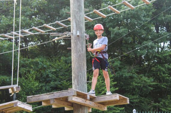 A camper in the middle of a ropes course.