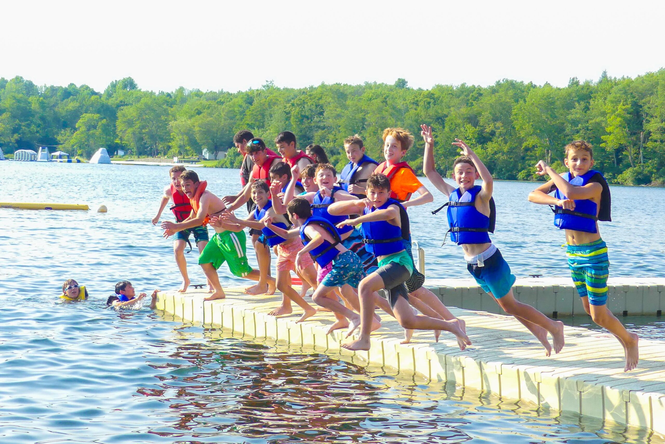 kids in life jackets jumping off a dock